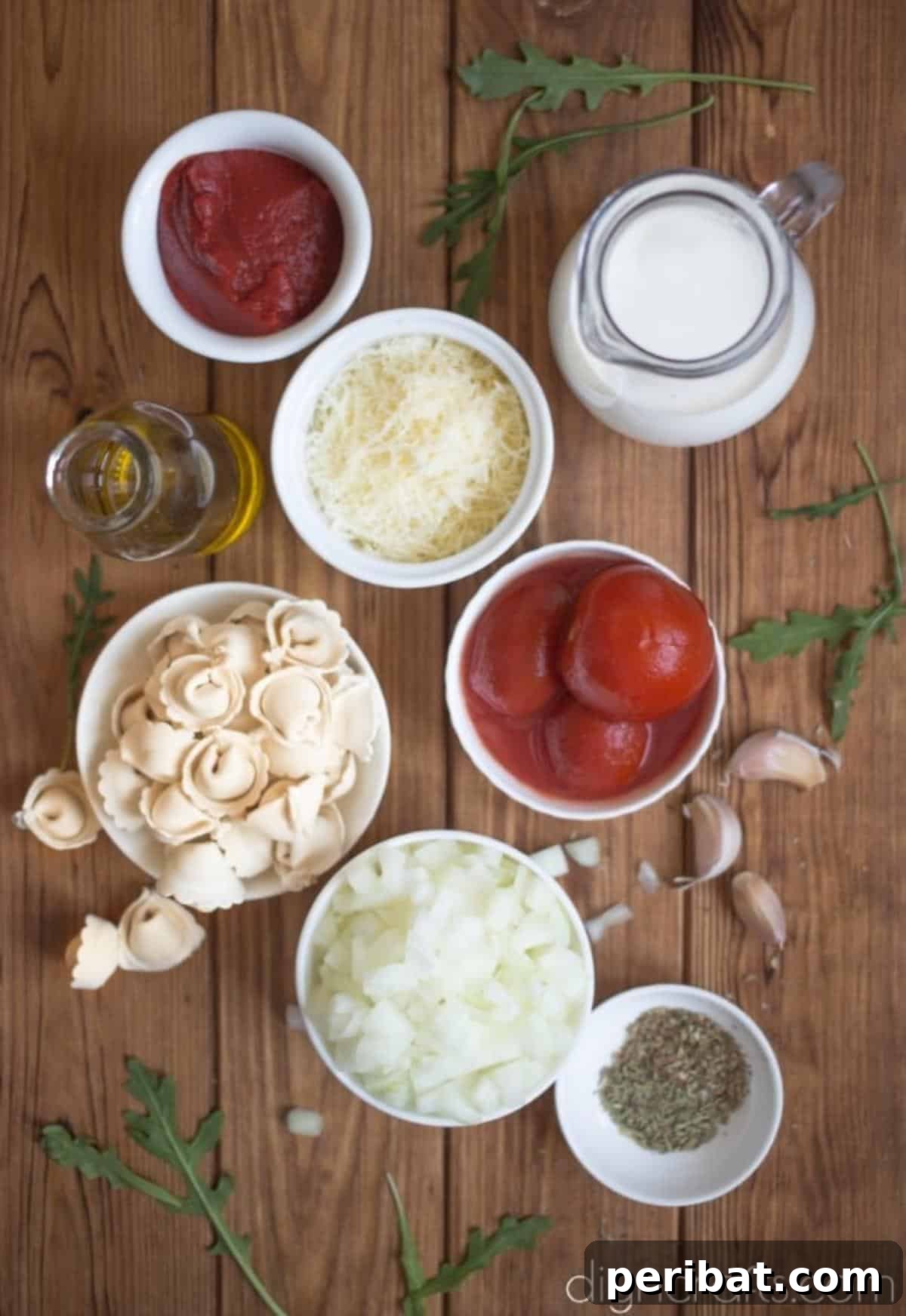 Fresh ingredients laid out for one-pot tortellini soup: onion, garlic, herbs, parmesan, crushed tomatoes, cream, and tortellini.