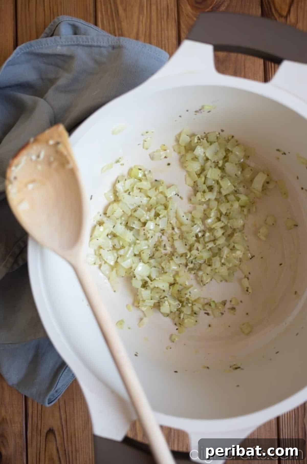 Diced onion, garlic, and herbs sautéing in olive oil in a single pot, releasing their fragrant aromas.