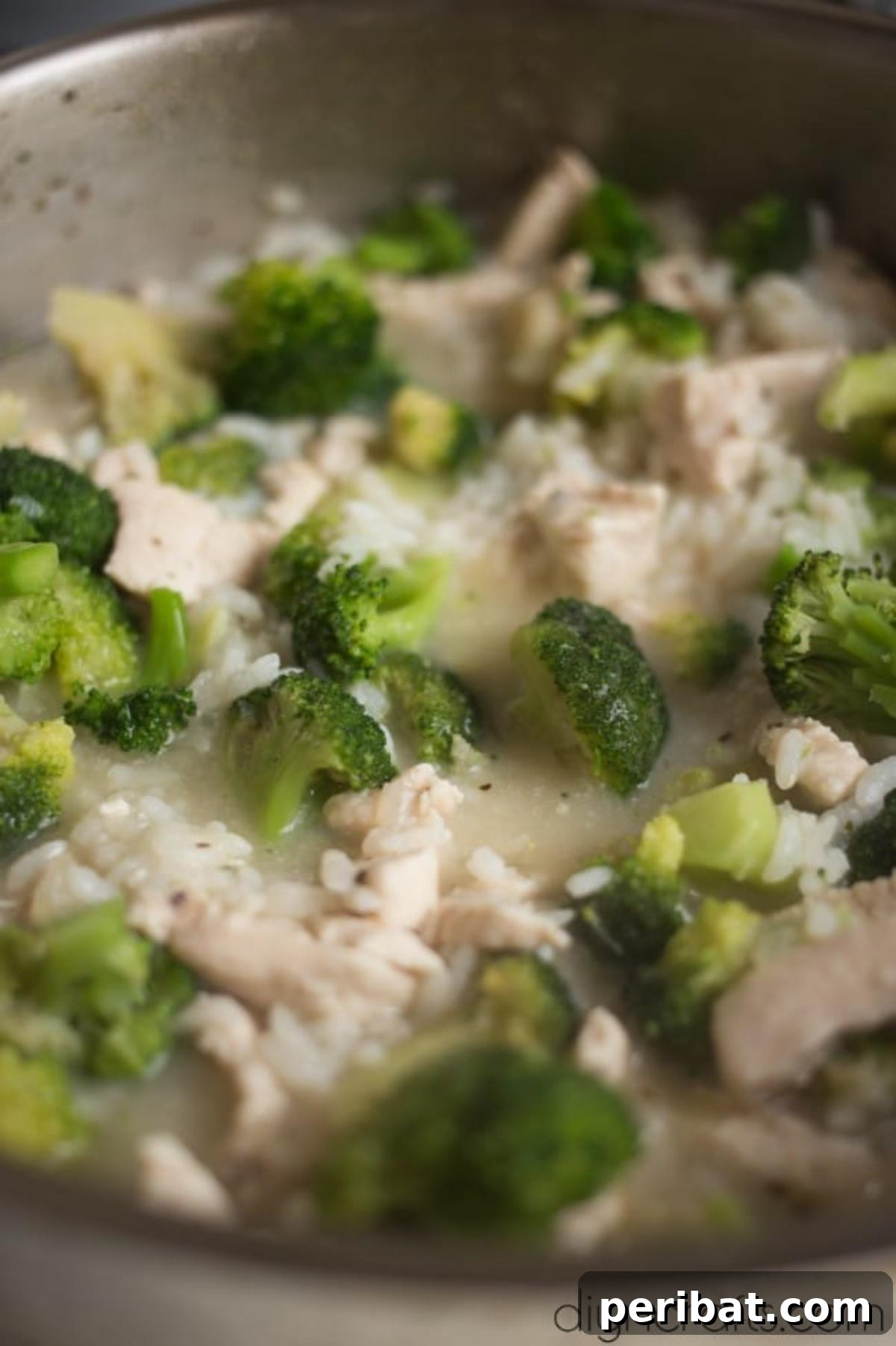 One-Pan Cheesy Chicken and Broccoli Rice Perfection 5 Vegetable broth being poured over chicken and rice in a pan