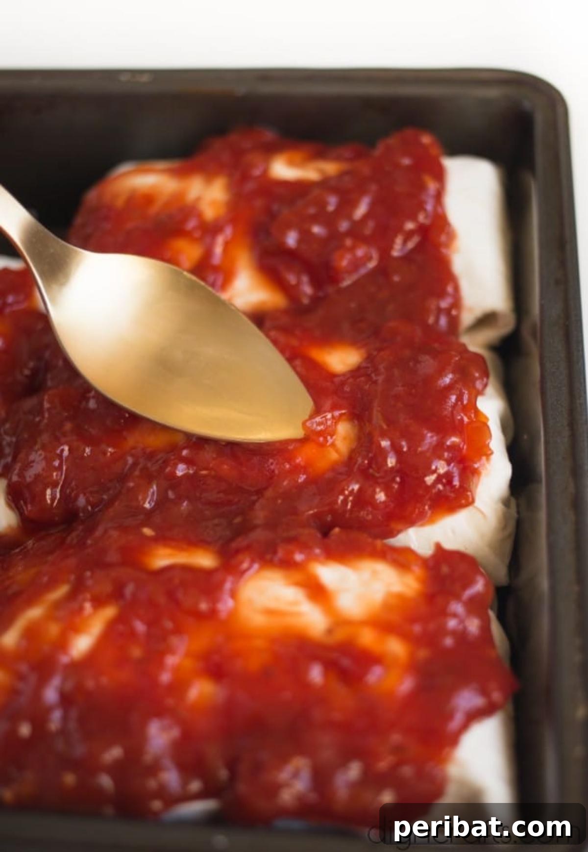 Vegan Burrito Power: High-Protein, Low-Fat Snacking Perfected 7 Baking vegan burritos in a baking pan, topped with homemade sauce.