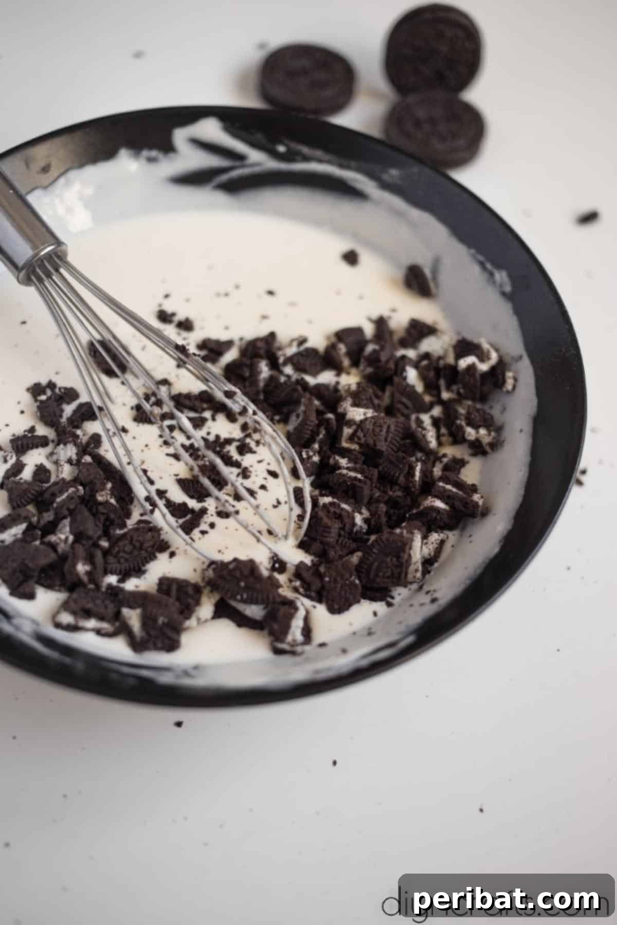 Filling for Oreo bites - A bowl of creamy cheesecake batter, visibly mixed with crushed Oreo pieces, showcasing its smooth texture and delightful inclusions.