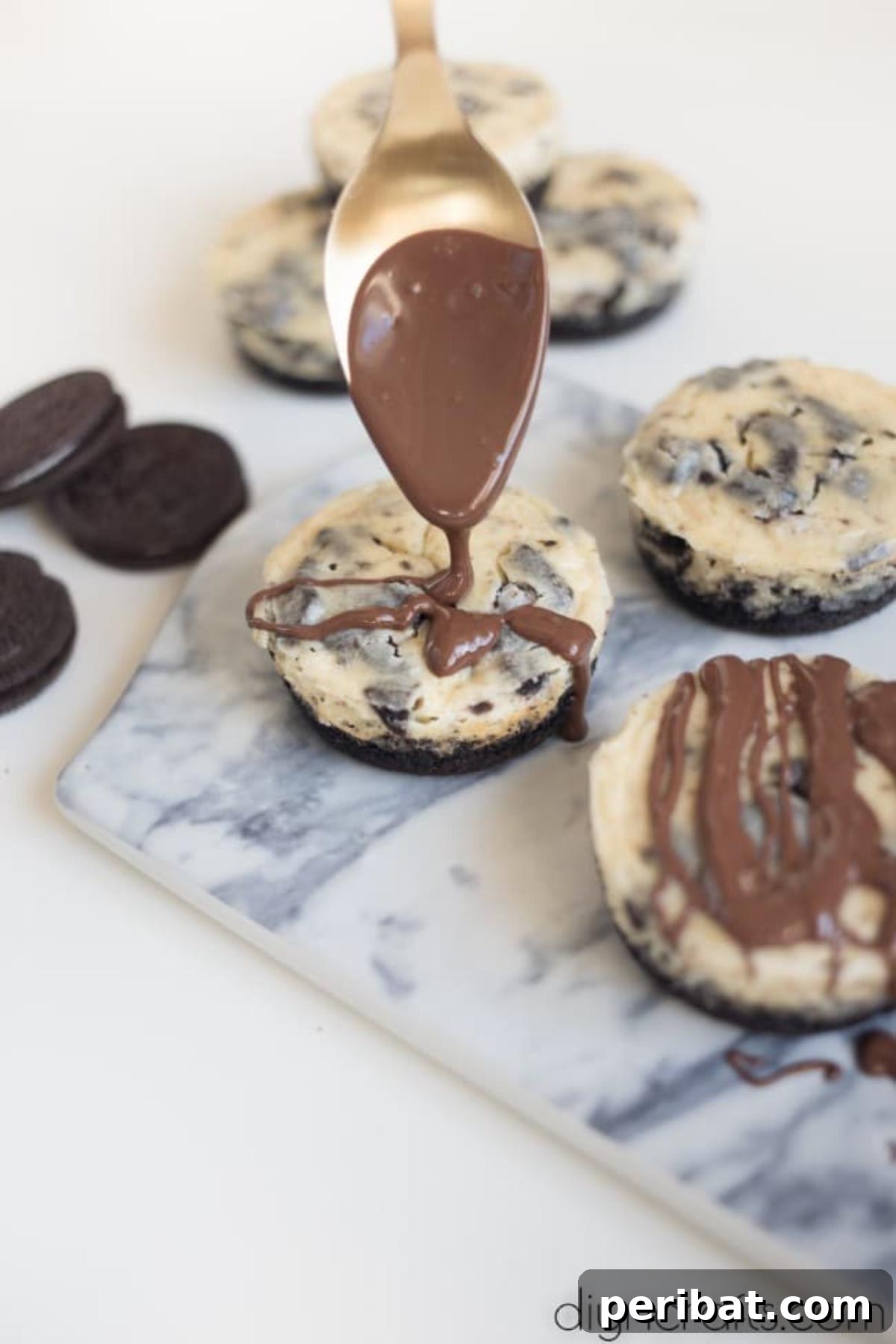 Drizzling chocolate over Oreo bites - Melted chocolate being elegantly drizzled from a spoon over the tops of baked Oreo cheesecake bites in a cupcake tray, adding a glossy finish.