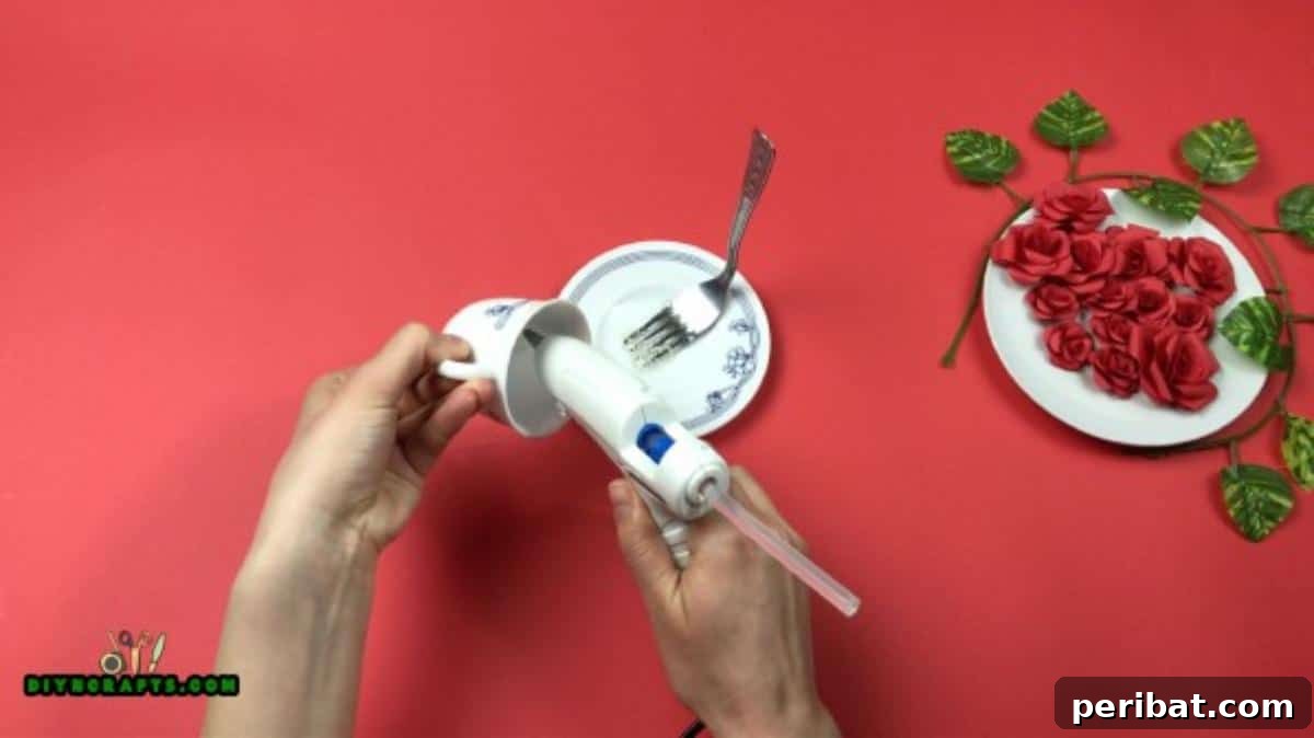 Whimsical Floating Teacup Centerpiece 4 Applying hot glue to the curved handle of the fork to precisely attach it to the side of the teacup.