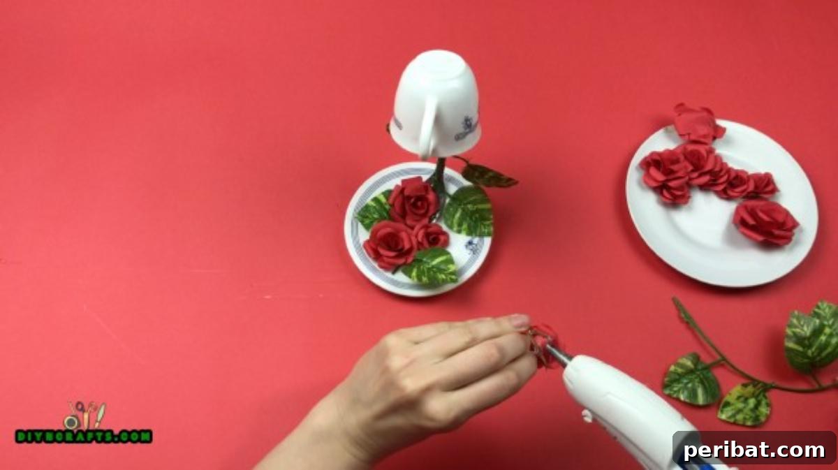Whimsical Floating Teacup Centerpiece 6 Applying hot glue to the fork handle and meticulously attaching artificial roses and foliage to completely cover it, creating a natural flower spill.
