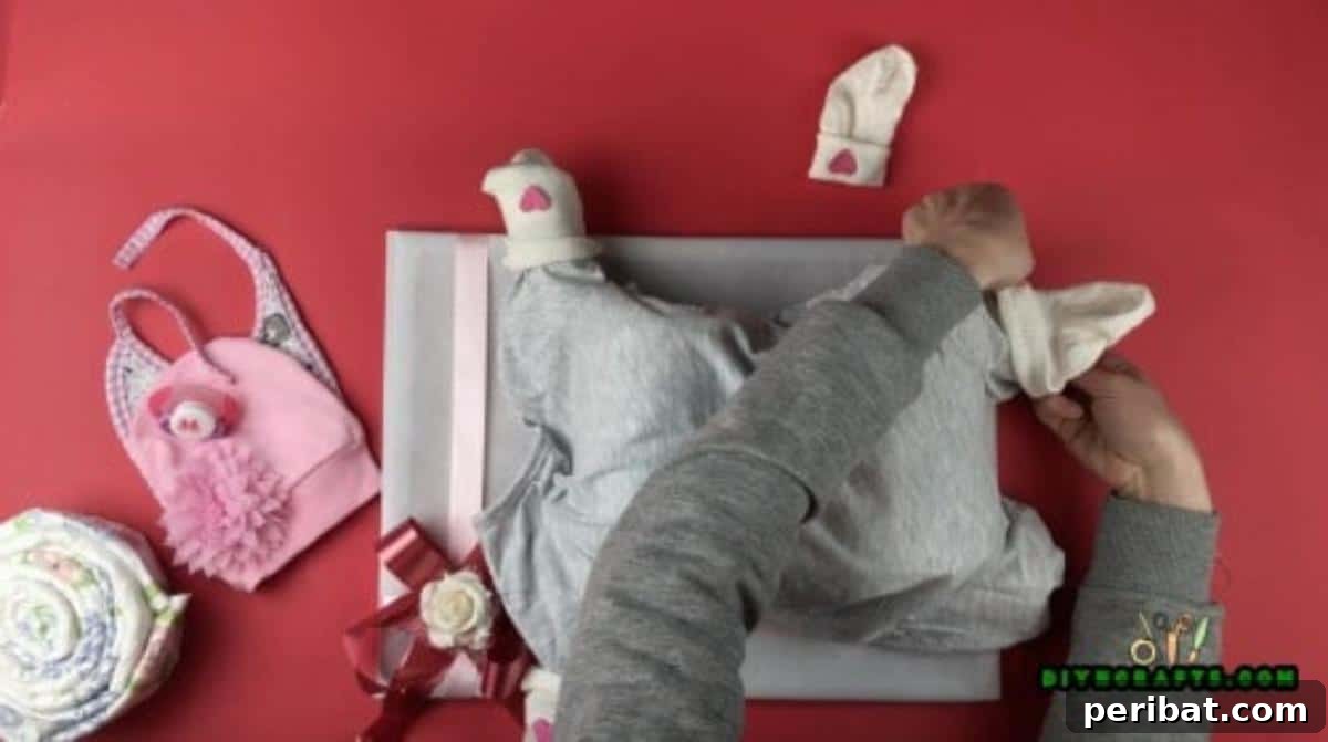 Crafting an Adorable Diaper Baby Gift 6 Hands carefully stuffing the rolled diaper 'arms' and 'legs' into the sleeves and pant legs of a baby coverall, demonstrating the process of giving the diaper baby its form.