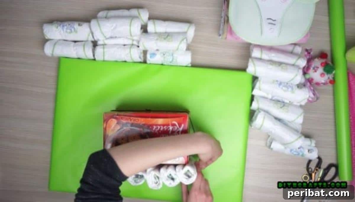 Continue rolling and placing diapers around the box to complete the first layer of the boat's structure.