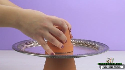 The smaller clay pot turned upside-down, ready for glue application on its rim.