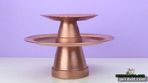 The final plate secured on top of the smaller pot, completing the multi-tiered structure.