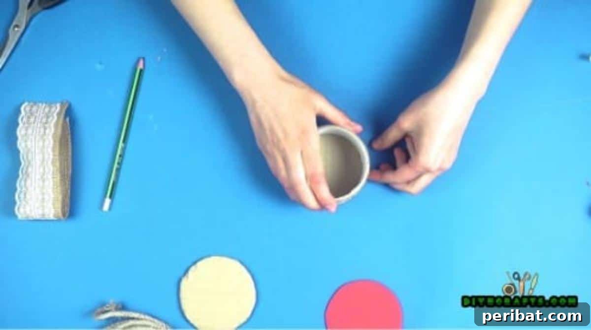 Applying hot glue to the rim of a cardboard circle before attaching the duct tape roll.