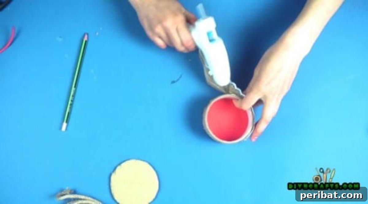 Gluing burlap fabric around the exterior of the duck tape roll to decorate the jewelry box.