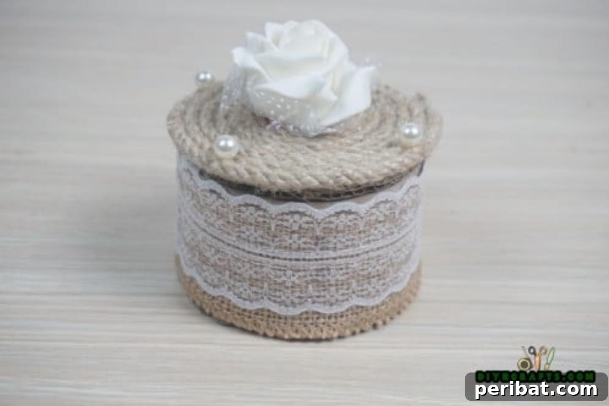 Finished DIY jewelry box crafted from a duct tape roll with a burlap exterior and twine lid.