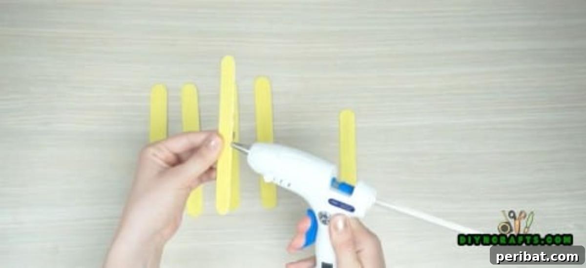Popsicle Stick Perfection: Easy DIY Napkin Holders 3 Use your hot glue gun to glue two of them together to form the base.