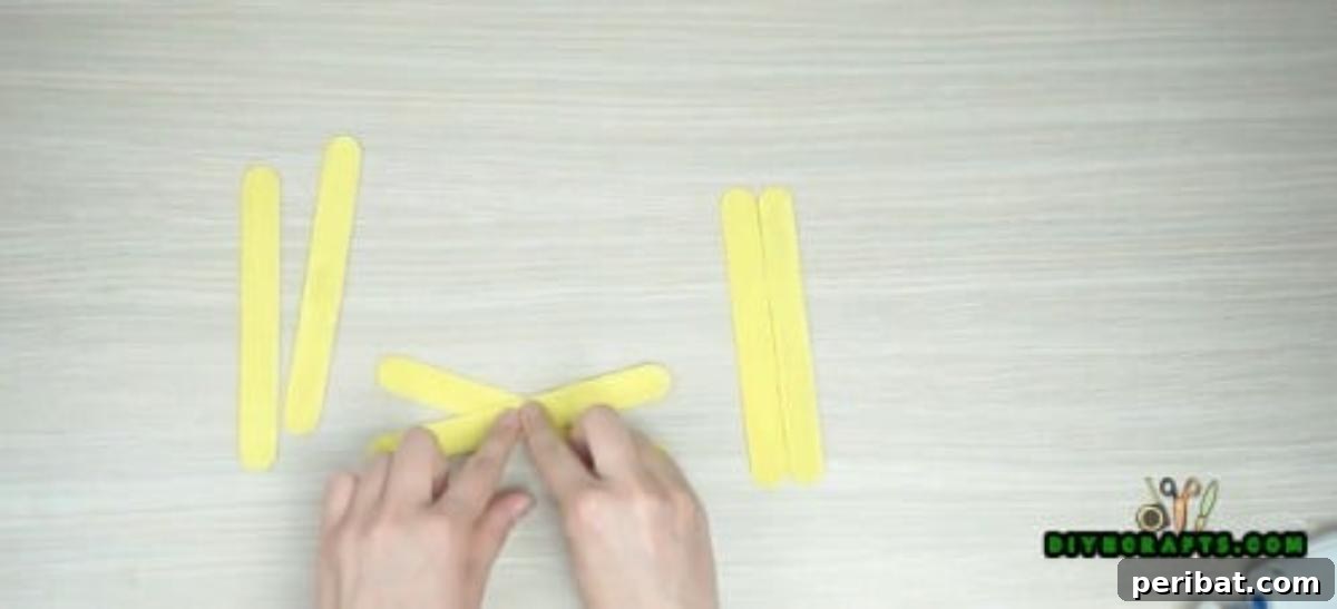 Popsicle Stick Perfection: Easy DIY Napkin Holders 5 Cross two of the popsicle sticks into an X-shape and glue them at the intersection.
