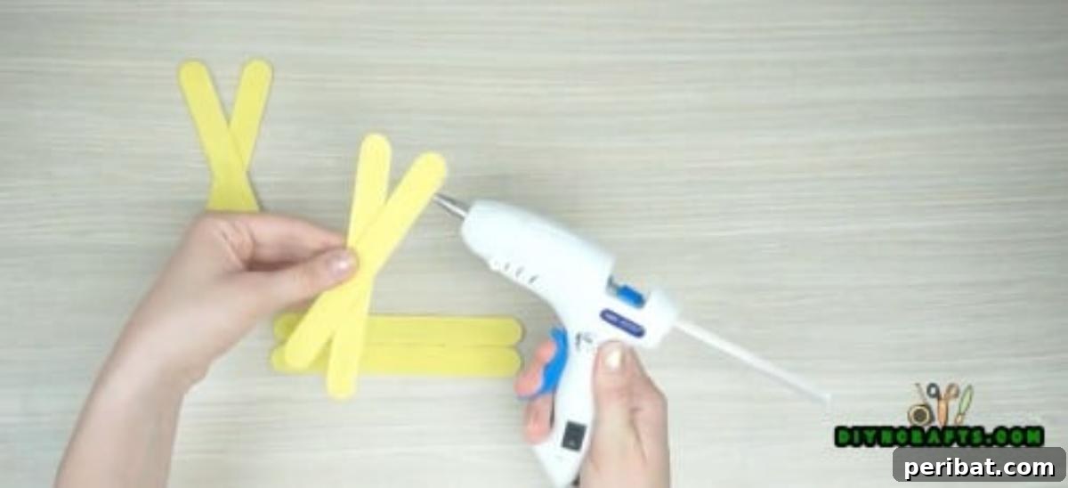 Popsicle Stick Perfection: Easy DIY Napkin Holders 6 Repeat the step above with the remaining two popsicle sticks to form a second X-shape.
