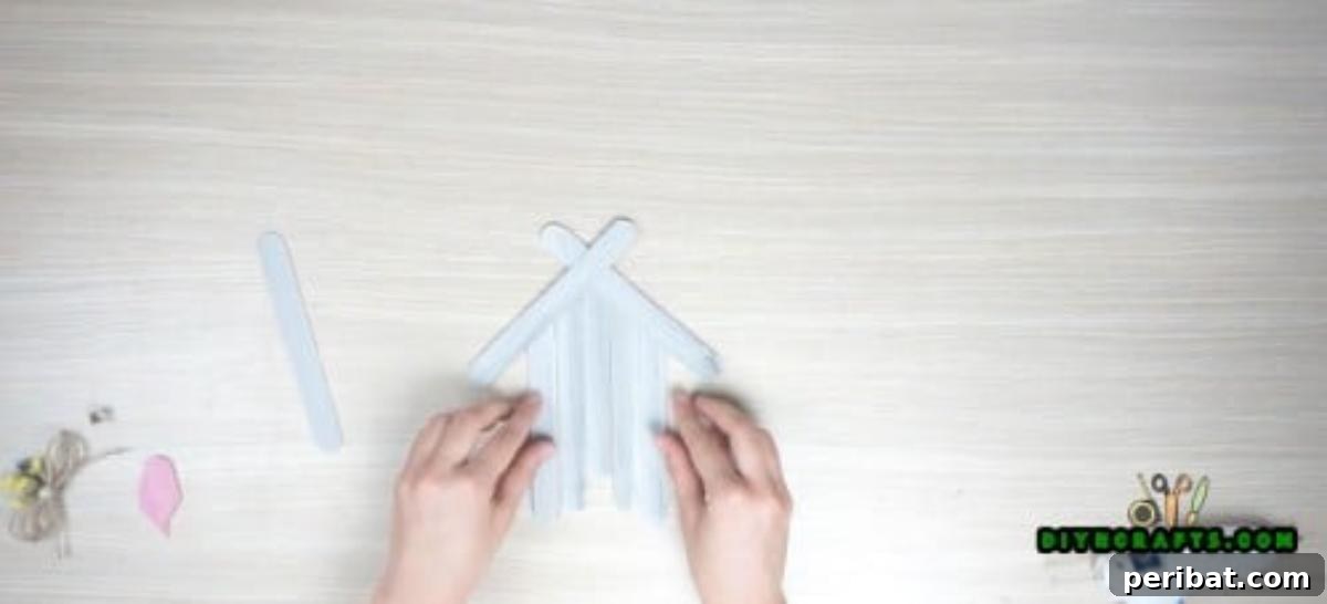 Transform Popsicle Sticks into Adorable Coasters 7 Gluing crisscrossed popsicle sticks to form the roof of the house coaster.
