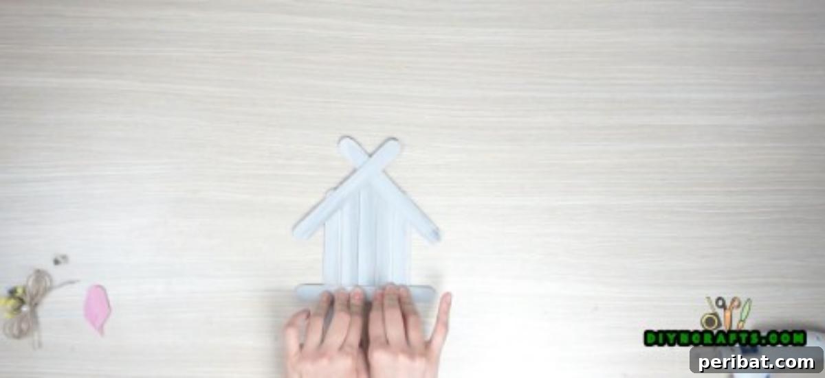 Transform Popsicle Sticks into Adorable Coasters 9 Stabilizing the glued stick, ensuring a flat and sturdy base for the house coaster.