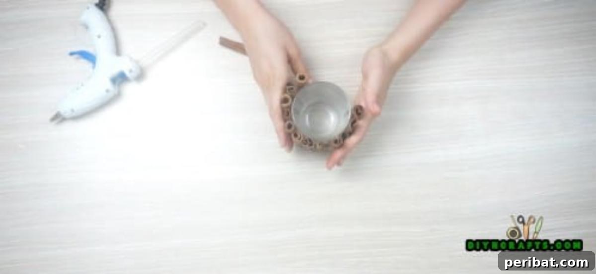 DIY Beautiful Candle Holders From Simple Materials 4 Attaching the first cinnamon stick to the votive cup, demonstrating precise placement for the DIY candle holder.