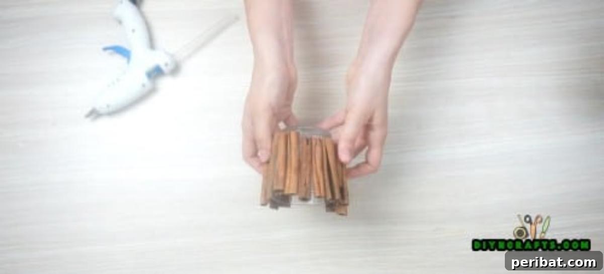 DIY Beautiful Candle Holders From Simple Materials 5 Progress shot of the cinnamon stick candle holder, with several sticks already glued around the glass votive, creating a rustic enclosure.