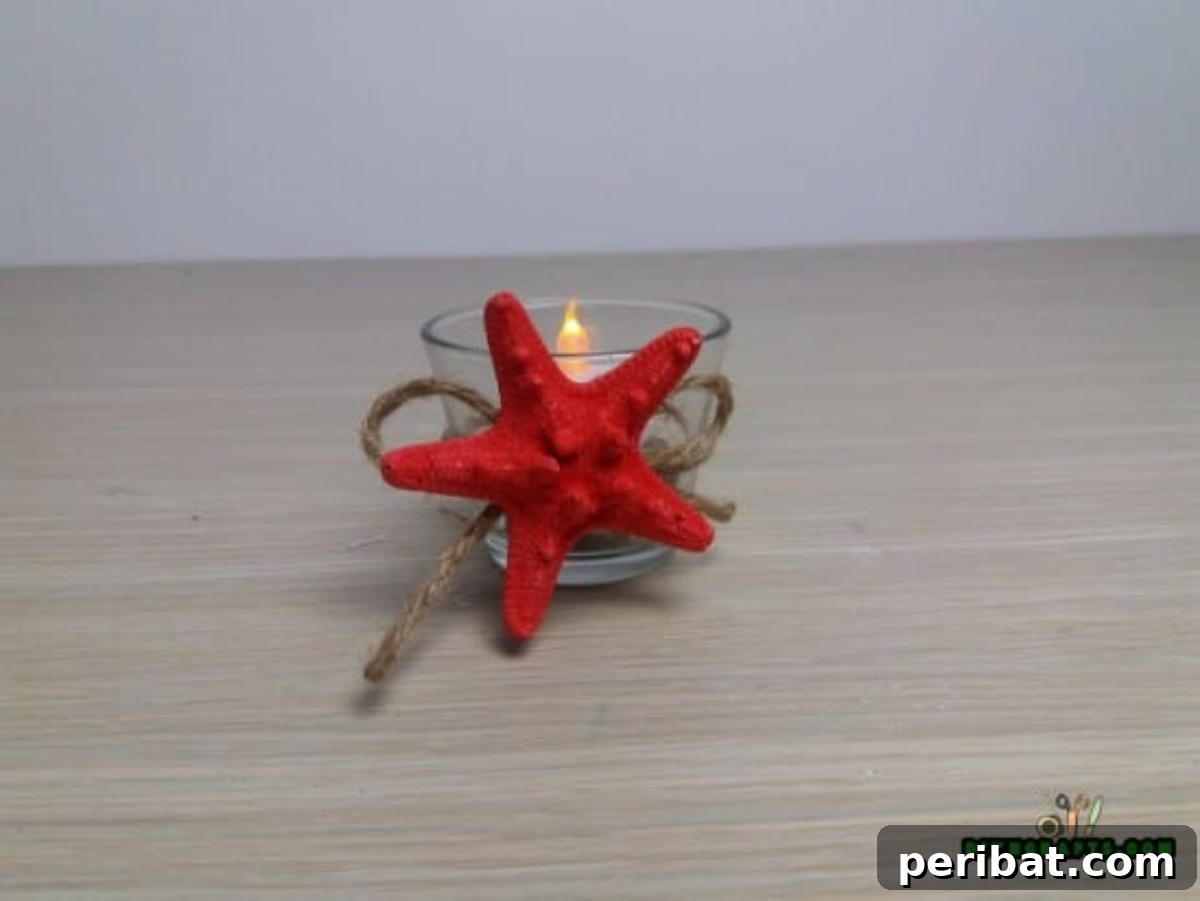 The finished stone and shell votive candle holder with a lit candle.