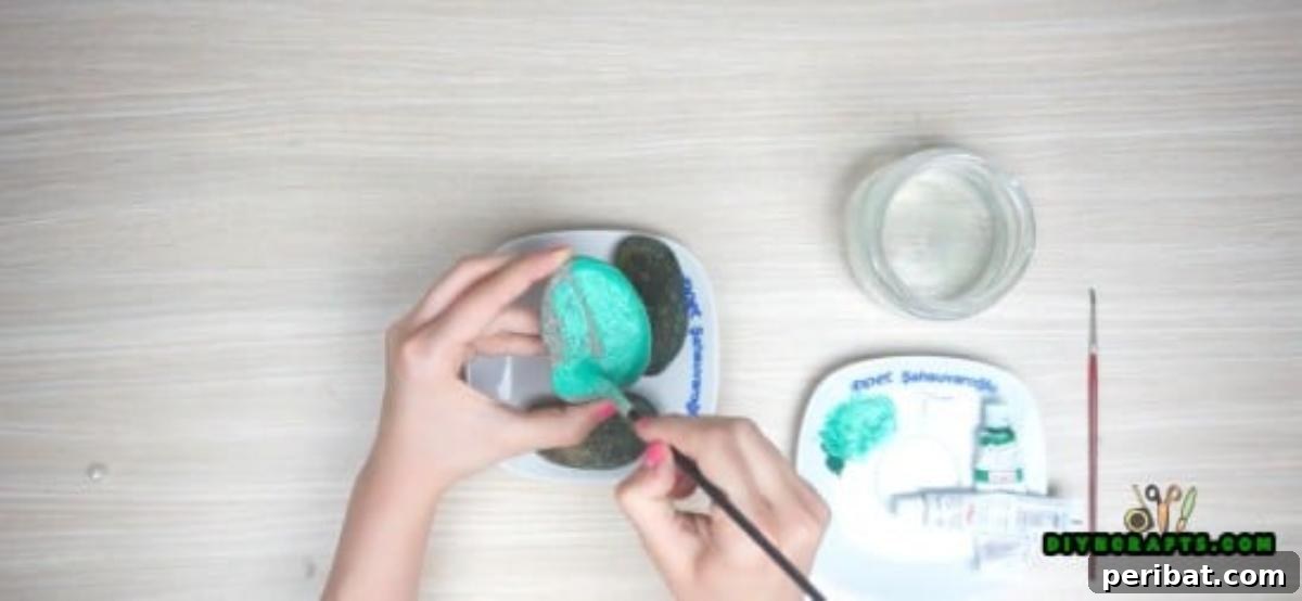 Painting rounded river rocks green and adding white details to create faux cacti.