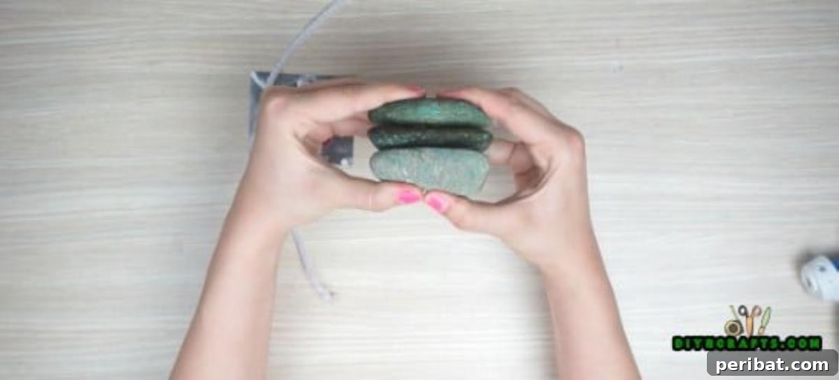 Gluing three medium river rocks together to form the base of a photo display.