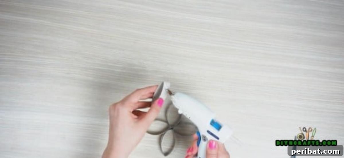 Assembling the last petal to complete the five-petal paper roll flower base for the DIY candle holder.