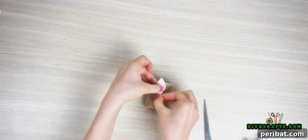 Adding decorative embellishments to a burlap-covered paper roll napkin ring.