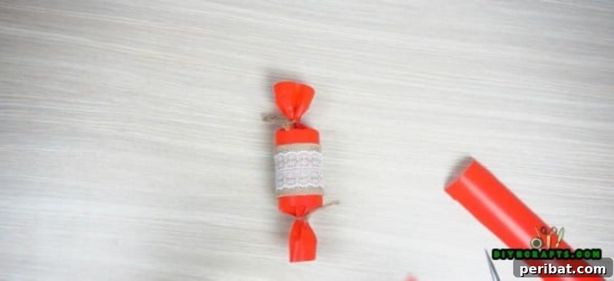 Lace being glued over burlap, enhancing the decorative candy made from a paper roll.