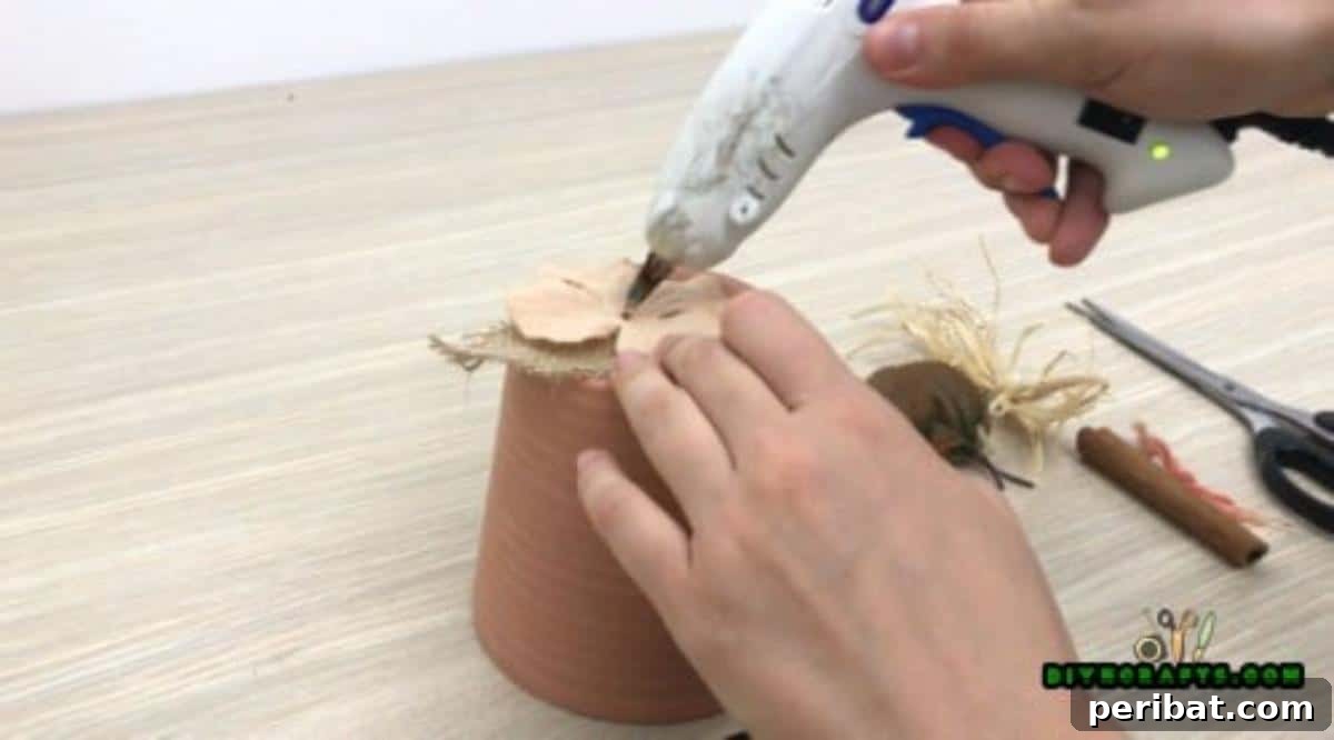 Arranging and gluing fake autumn-colored flowers onto the burlap base