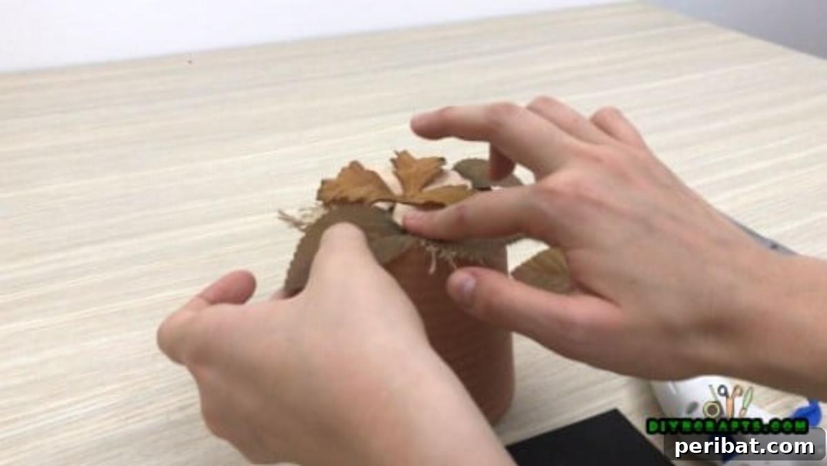 Adding fake autumn leaves to complement the flowers on the flower pot decoration