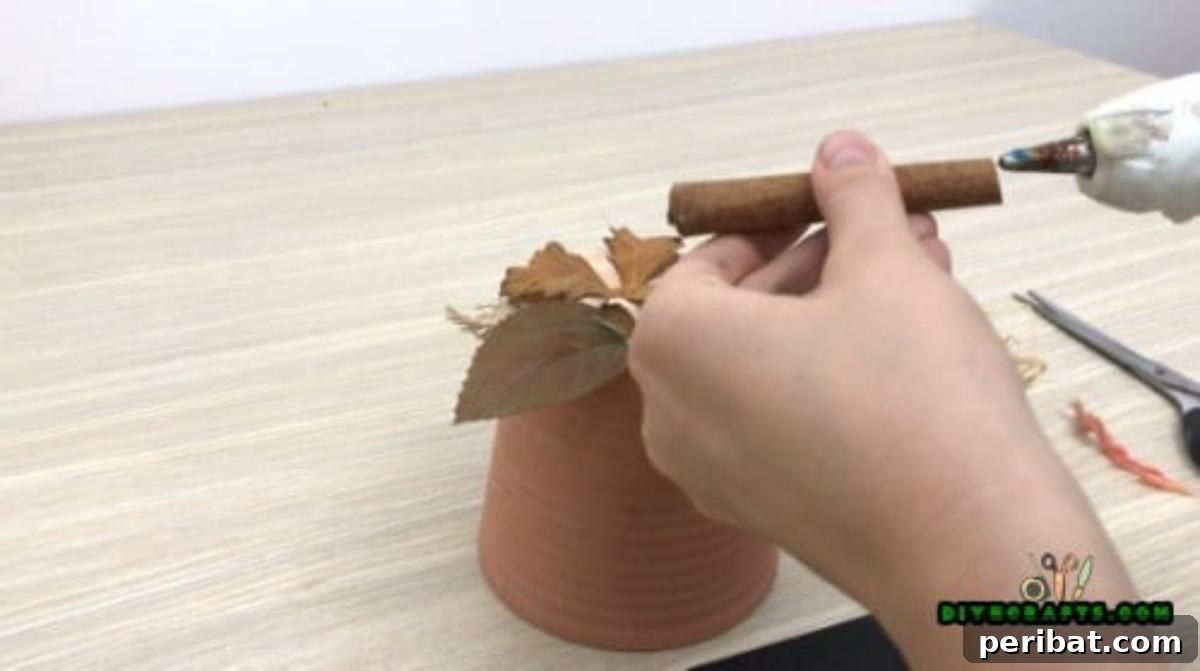 Gluing the cinnamon stick upright in the center as the pumpkin's stem
