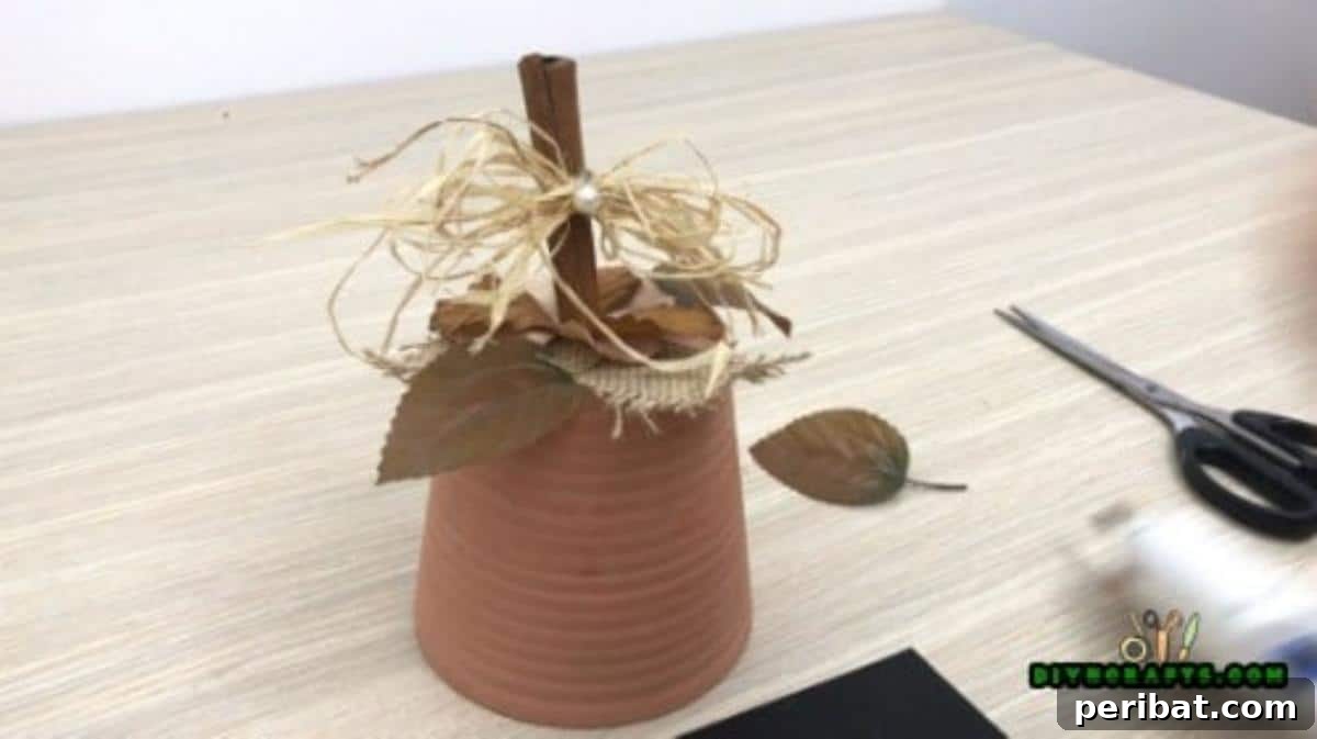 Tying straw and adding a small glass pearl embellishment around the cinnamon stick stem
