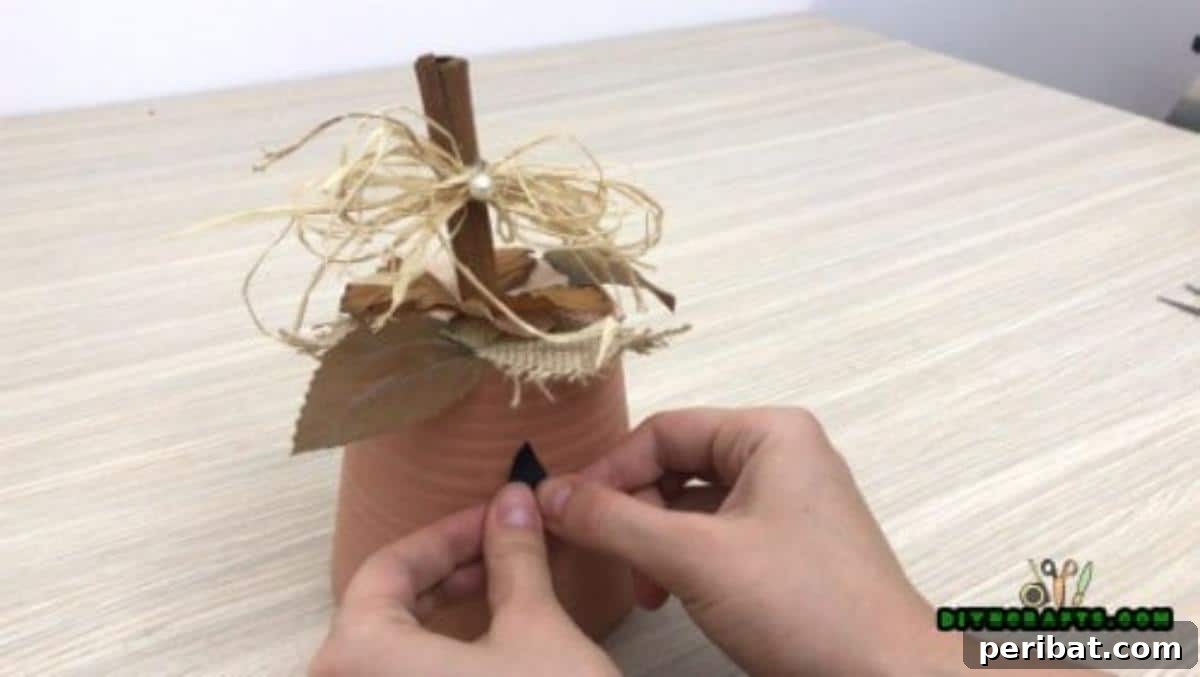 Gluing the black paper eye shapes onto the flower pot to form the jack-o-lantern face