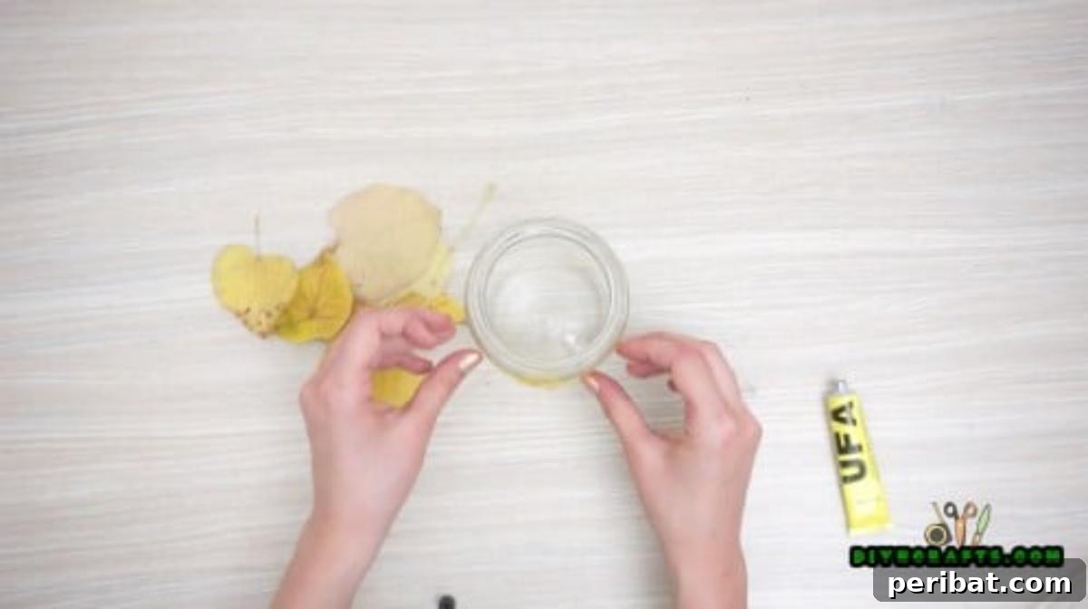 Minutes to Marvelous: 5 Easy Fall DIY Decor Projects 14 Attaching autumn leaves to the outside of a clear glass jar using a glue stick, creating a layered, mosaic effect.
