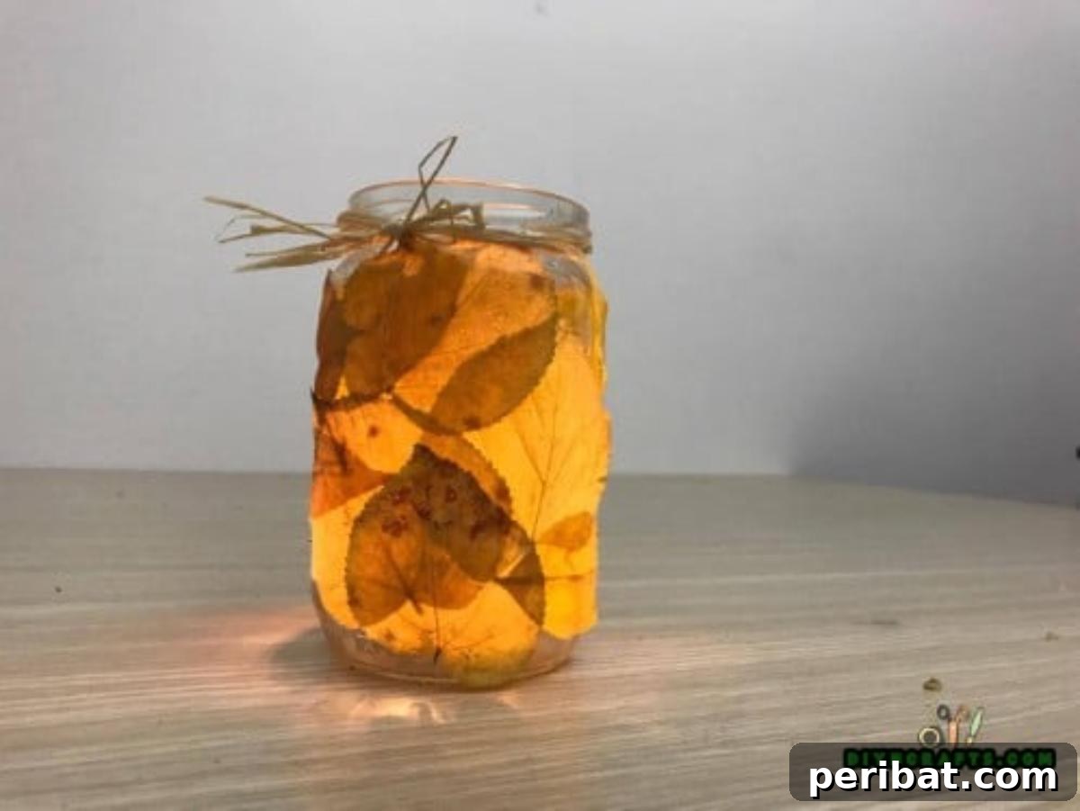 Minutes to Marvelous: 5 Easy Fall DIY Decor Projects 16 The finished autumn leaf jar, elegantly decorated with twine around the neck and glowing softly with an LED votive light inside, creating a warm ambiance.