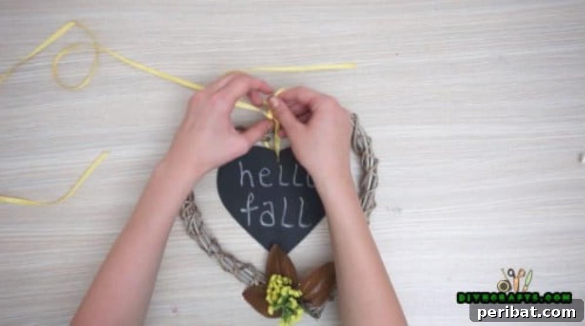 Minutes to Marvelous: 5 Easy Fall DIY Decor Projects 21 The 'Hello Fall' sign hung gracefully in the center of the richly decorated autumn wreath using a coordinating ribbon, ready for display.