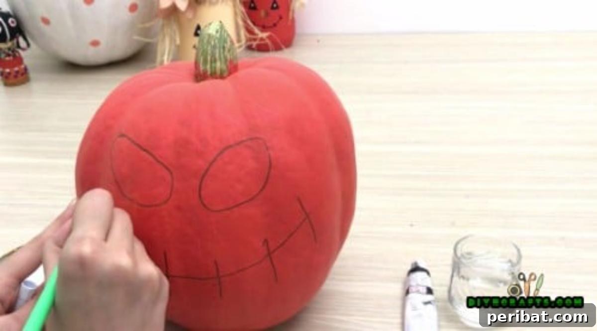 Step 2: Sketching the mouth design onto the pumpkin with a pencil, defining its character before painting.