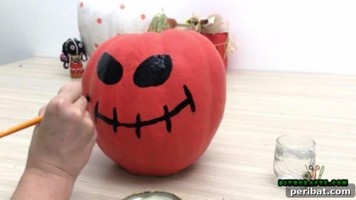 Step 4: Painting the sketched mouth of the pumpkin with black paint, completing its spooky face.