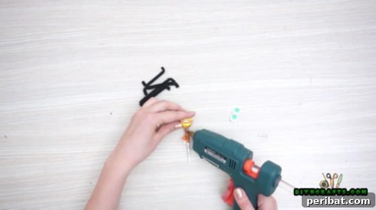 Step 2: Attaching pipe cleaner segments to the lollipop stick with hot glue, forming the spider's legs.