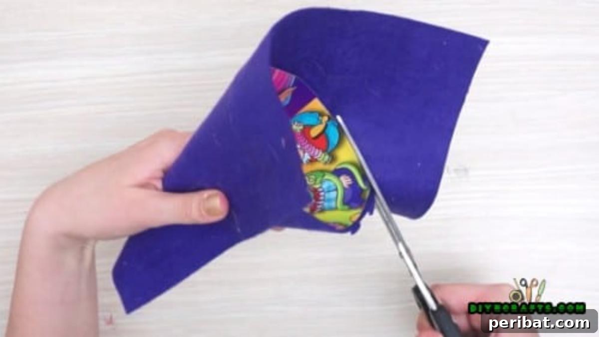 Step 2: Trimming the decorative paper around the cone to create a neat and fully covered witch hat base.