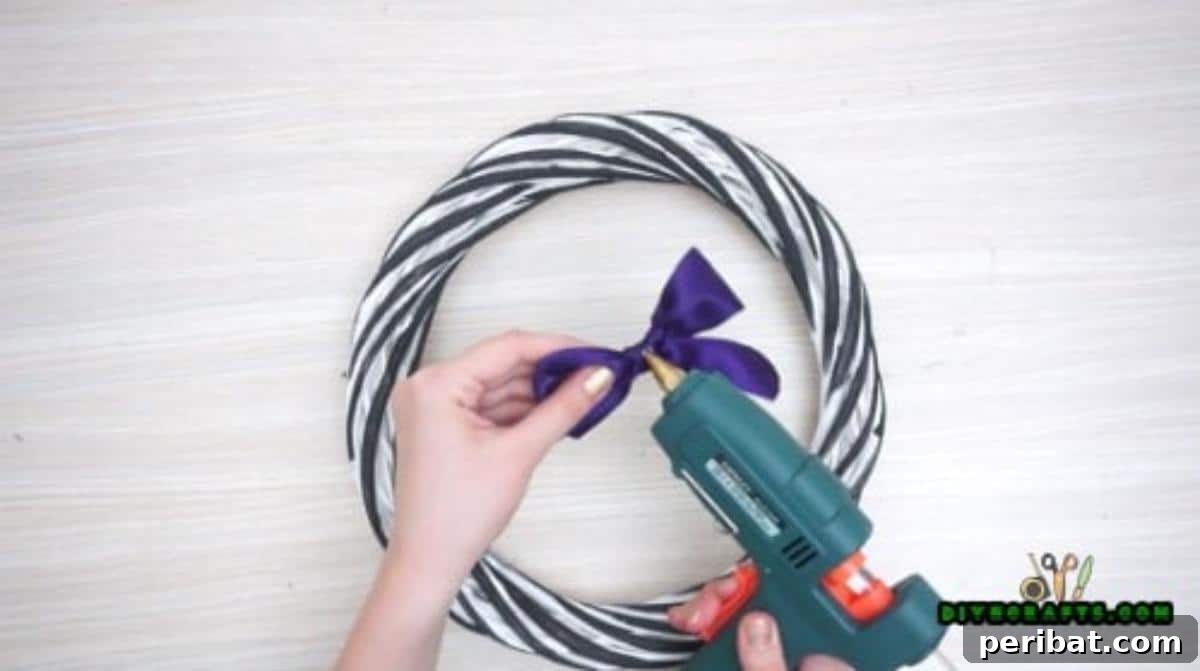 Step 1: Attaching a decorative bow to a simple store-bought wreath, setting the base for a Halloween design.