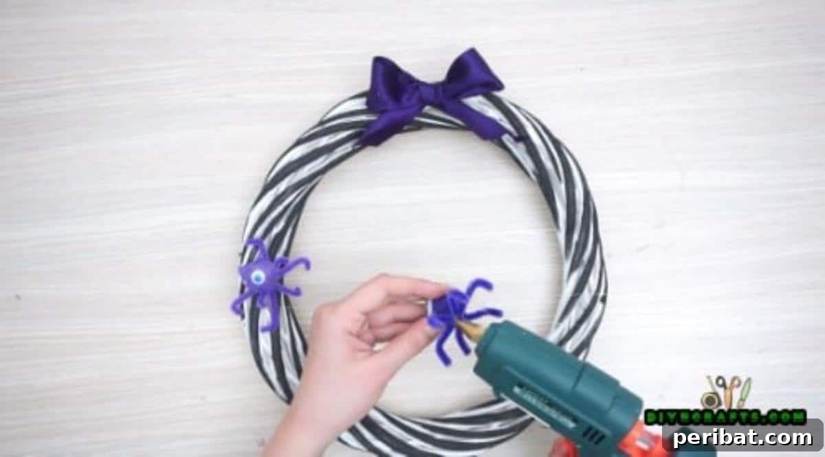 Step 2: Adding pipe cleaner critters and other small Halloween decorations to the wreath with hot glue.
