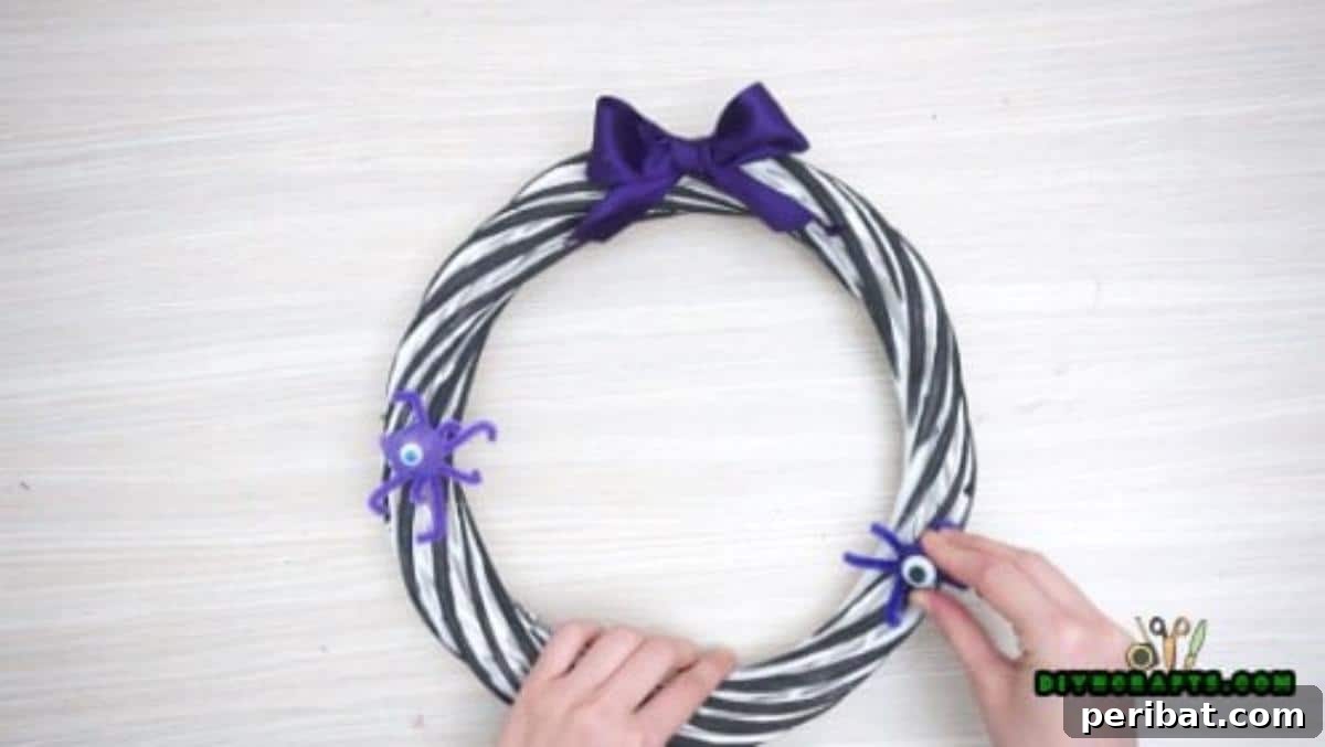 Step 2 continued: Further embellishing the wreath with additional Halloween-themed elements, creating a festive look.