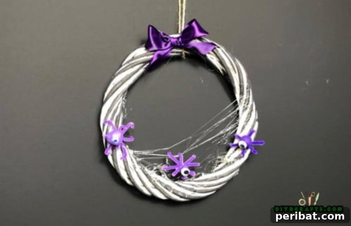 Completed Halloween Wreath, adorned with a bow, pipe cleaner critters, and a touch of fake cobweb, ready for display.