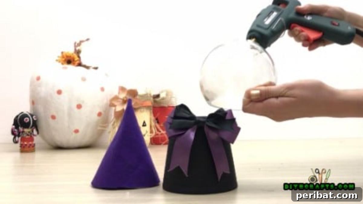 Step 4: Attaching a plastic or glass bowl to the inverted flower pot with hot glue, forming the witch's head.