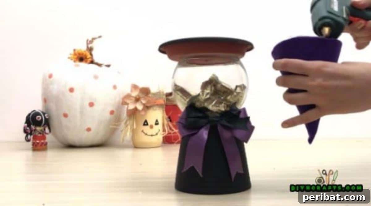 Step 6: Placing the flower pot's water collection tray on top of the candy-filled bowl, acting as the witch's hat brim.