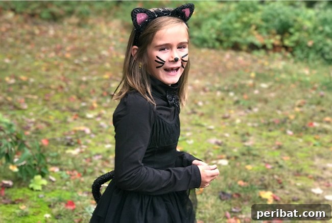 75 Effortless DIY Halloween Costumes That Kids Adore 3 A young girl smiling brightly while wearing an adorable DIY kitty cat Halloween costume outdoors, complete with ears and a tail