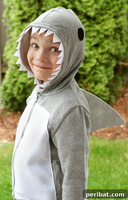75 Effortless DIY Halloween Costumes That Kids Adore 67 A child in a cool 'Shark' costume for Halloween, featuring a gray zip-up sweatshirt with white felt teeth on the hood and a cardboard fin, an easy DIY idea