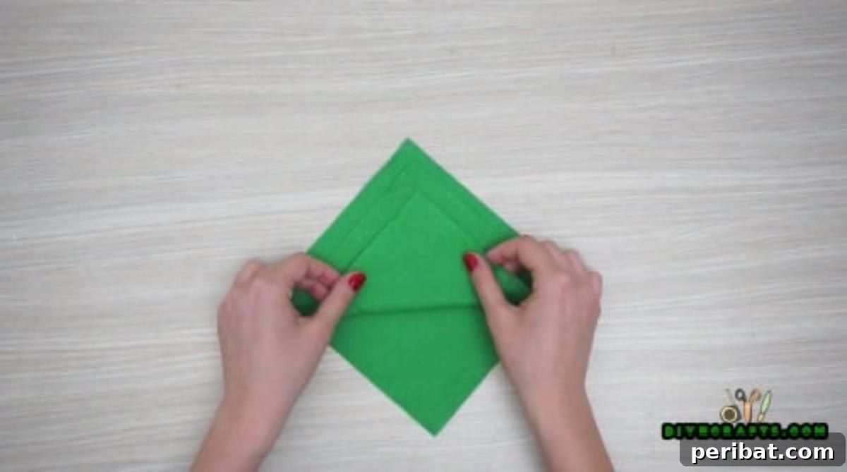 5 DIY Christmas Napkin Designs: Festive Folds, Easy Video How-To 11 Tree Napkin - Continue folding napkin sections for tiered Christmas tree effect, easy holiday craft.