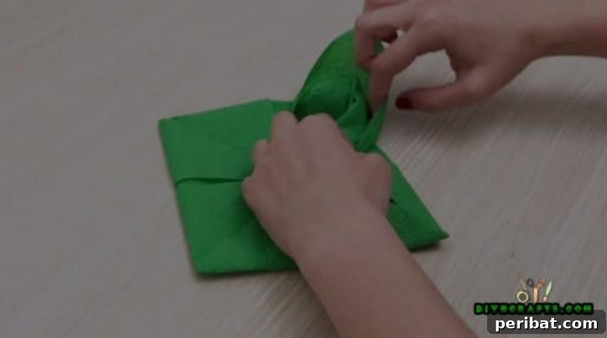 5 DIY Christmas Napkin Designs: Festive Folds, Easy Video How-To 22 Fancy Napkin - Detailed step on pulling napkin corners to create elegant, intricate petals.